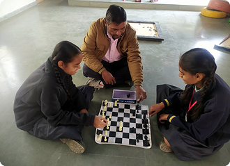 Students playing chess with their sports teacher