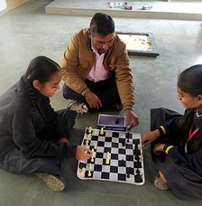 Students playing chess with their sports teacher